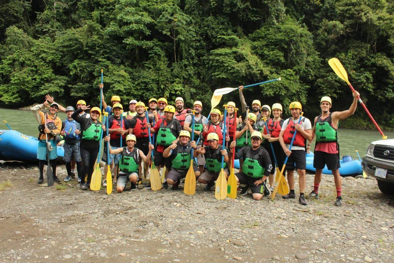 Grupo grande con remos a la orilla del río después del rafting