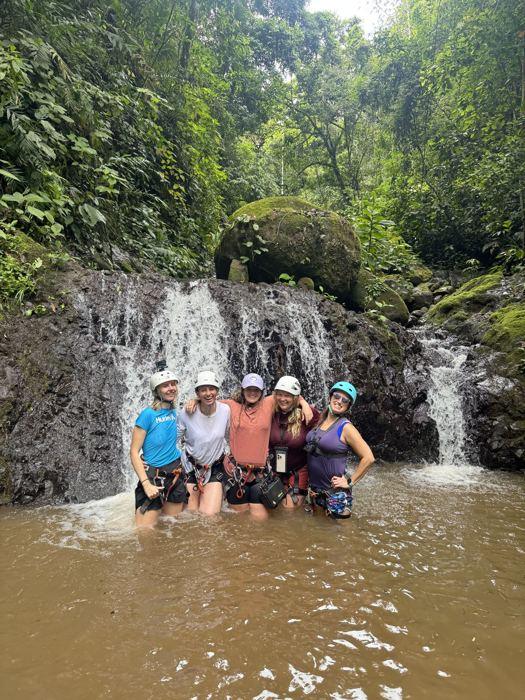 Grupo sonriendo dentro de la poza frente a la catarata