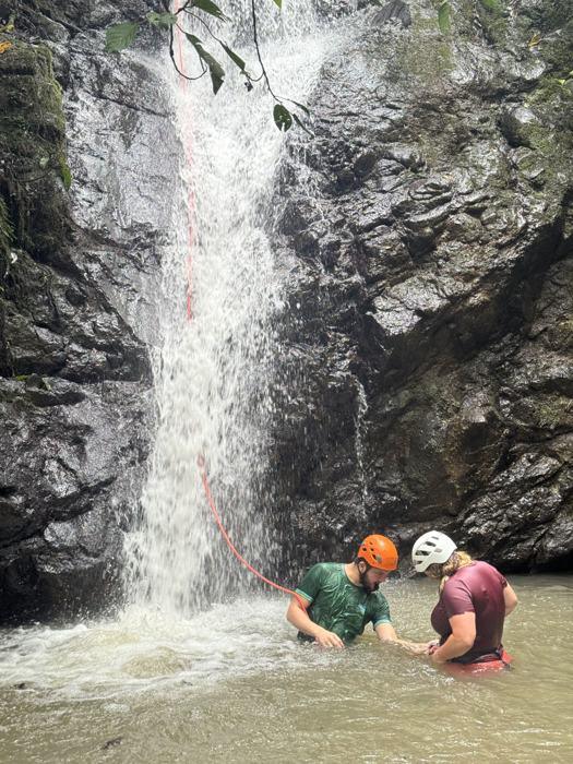 Guía y participante al pie de una cascada
