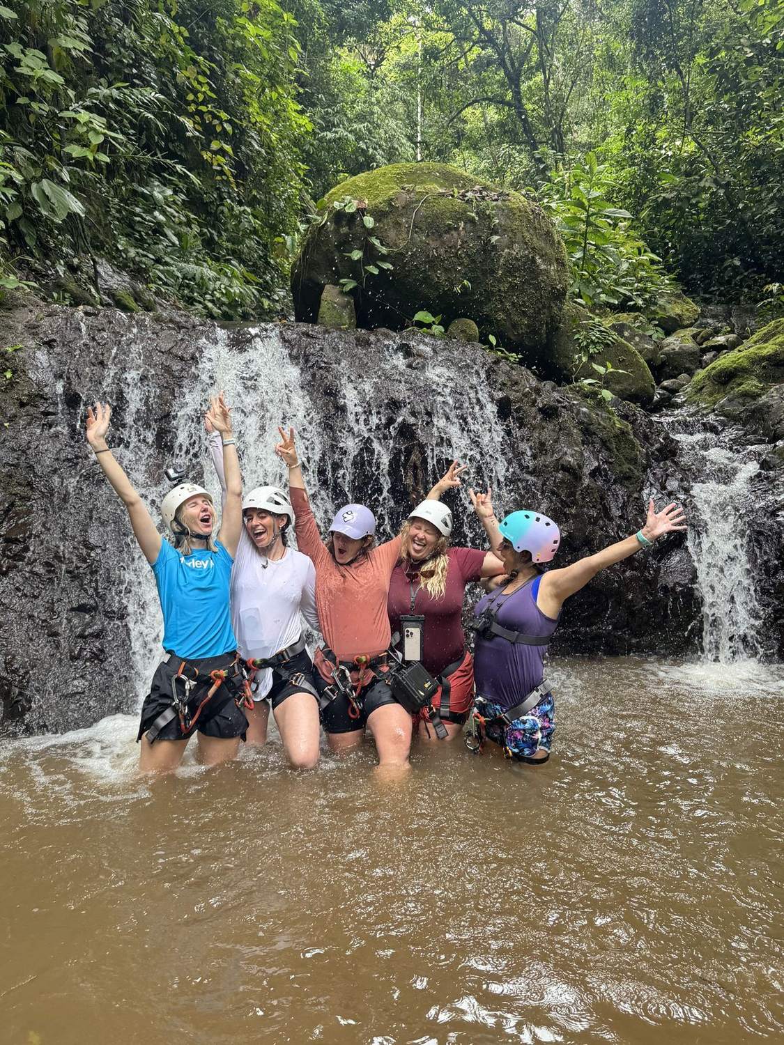 Grupo celebrando bajo una catarata durante un tour de canyoning